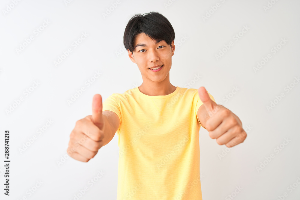Chinese man wearing yellow casual t-shirt standing over isolated white background approving doing positive gesture with hand, thumbs up smiling and happy for success. Winner gesture. Chinese man wearing yellow casual t-shirt standing over isolated white background approving doing positive gesture with hand, thumbs up smiling and happy for success. Winner gesture.