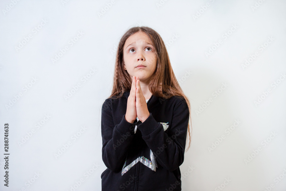 Little brunette girl praying. The child looks up Little brunette girl praying. The child looks up