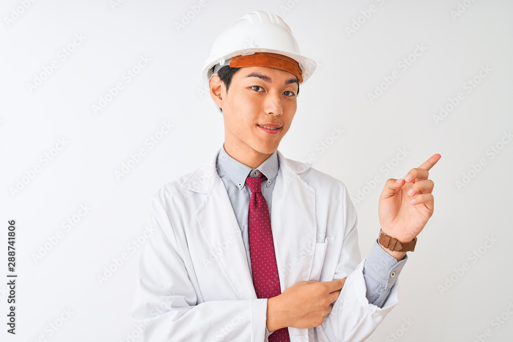 Chinese architect man wearing coat and helmet standing over isolated white background with a big smile on face, pointing with hand and finger to the side looking at the camera. Chinese architect man wearing coat and helmet standing over isolated white background with a big smile on face, pointing with hand and finger to the side looking at the camera.