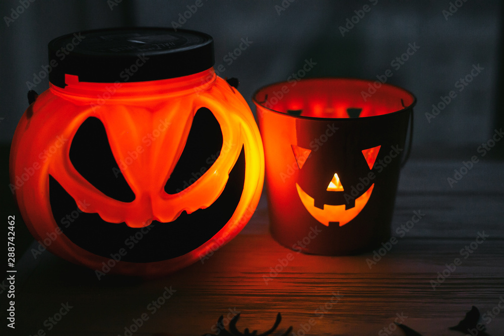 Happy Halloween. Glowing Jack-o-lantern face in dark. Spooky atmospheric jack o lantern glowing pumpkin bucket on black background. Trick or treat. Copy space
