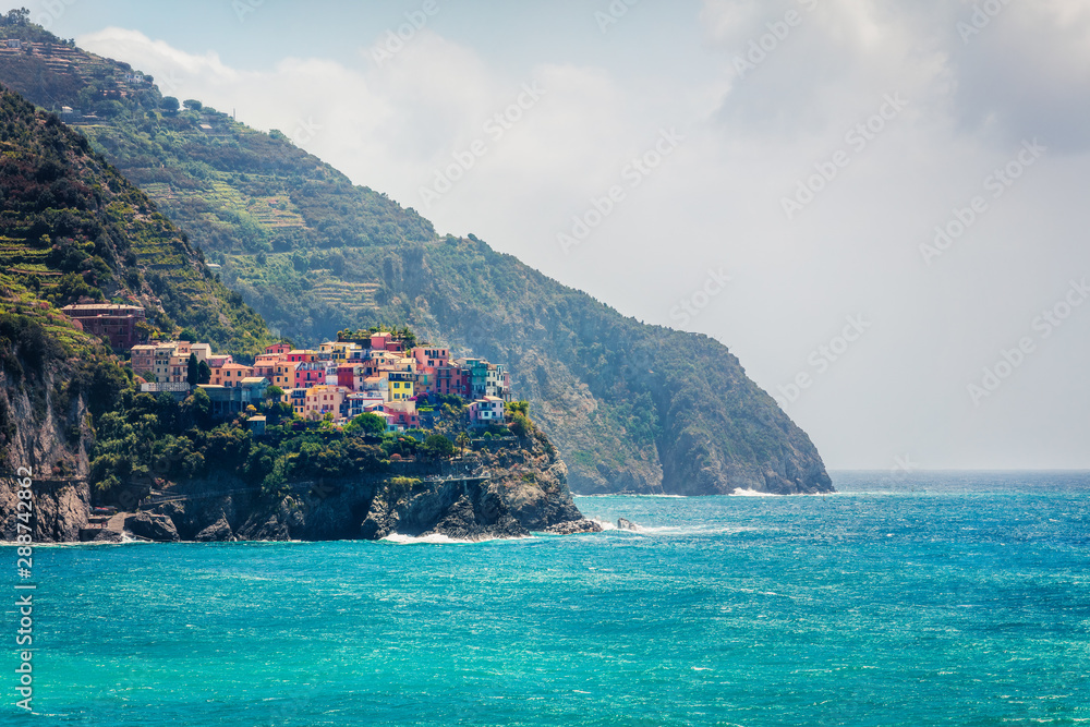 Second city of the Cique Terre sequence of hill cities - Manarola, view from Corniglia town. Misty spring morning in Liguria, Italy, Europe. Picturesqie seascape of Mediterranean sea.