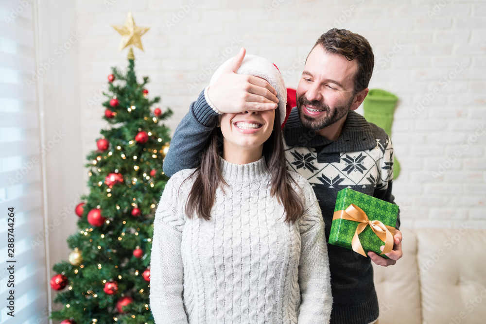 Man Surprising Lover With Christmas Gift At Home Man Surprising Lover With Christmas Gift At Home