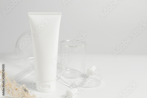 beauty spa medical skincare concept, cosmetic lotion bottle packaging on white decor background with science doctor laboratory test glass