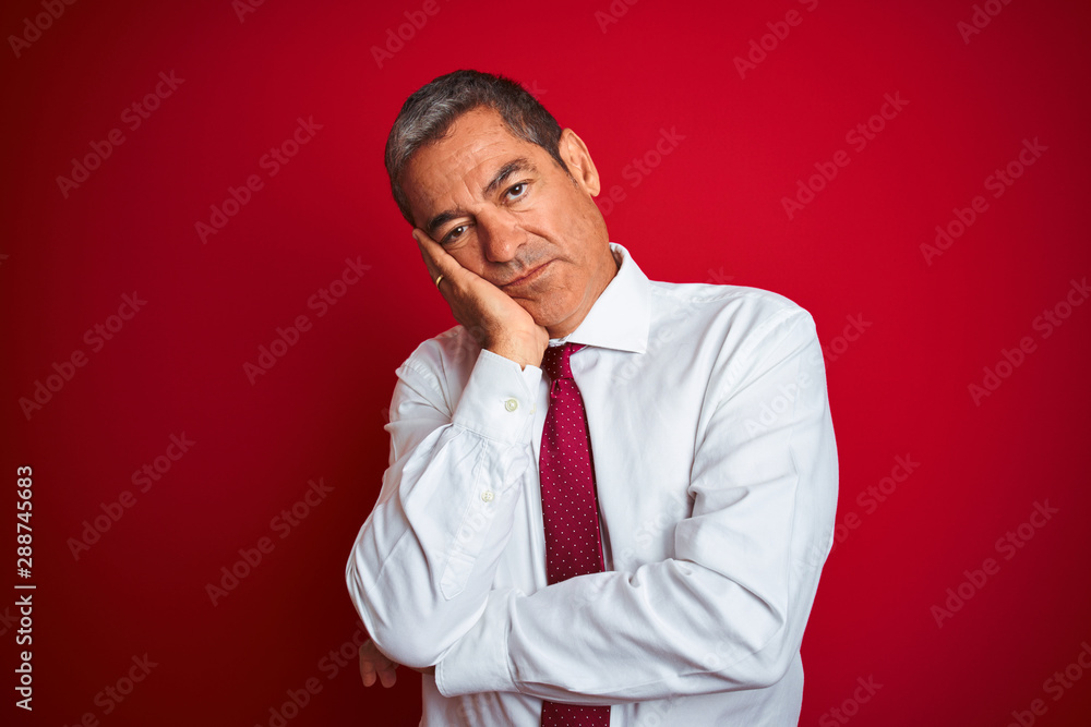 Handsome middle age businessman standing over isolated red background thinking looking tired and bored with depression problems with crossed arms. Handsome middle age businessman standing over isolated red background thinking looking tired and bored with depression problems with crossed arms.