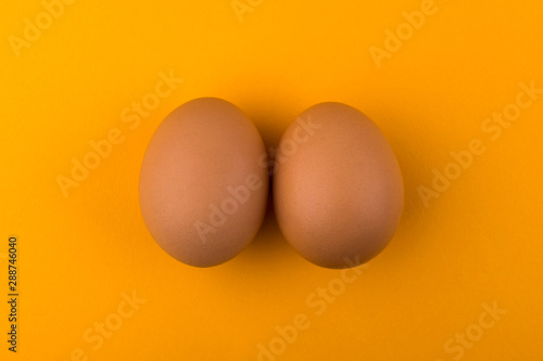 Brown chicken eggs lie on an orange background