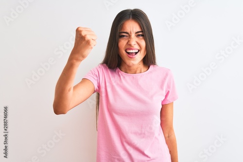Wallpaper Mural Young beautiful woman wearing pink casual t-shirt standing over isolated white background angry and mad raising fist frustrated and furious while shouting with anger. Rage and aggressive concept. Torontodigital.ca