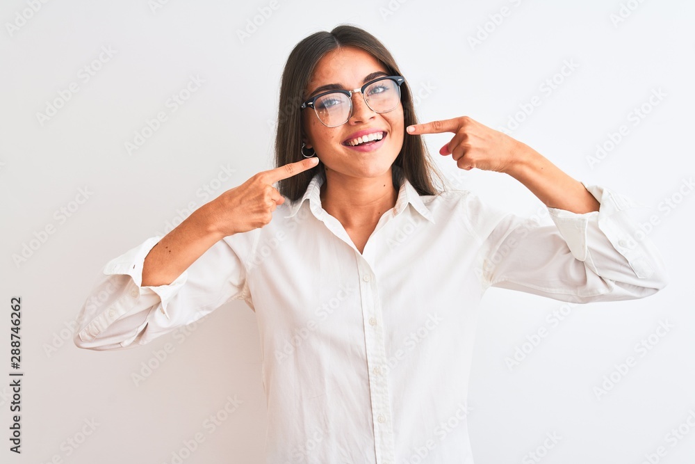 Young beautiful businesswoman wearing glasses standing over isolated white background smiling cheerful showing and pointing with fingers teeth and mouth. Dental health concept. Young beautiful businesswoman wearing glasses standing over isolated white background smiling cheerful showing and pointing with fingers teeth and mouth. Dental health concept.