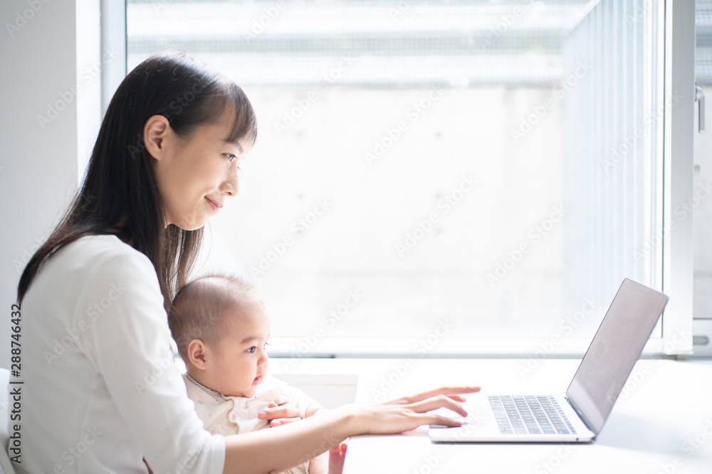 Young woman using laptop computer with her baby Young woman using laptop computer with her baby