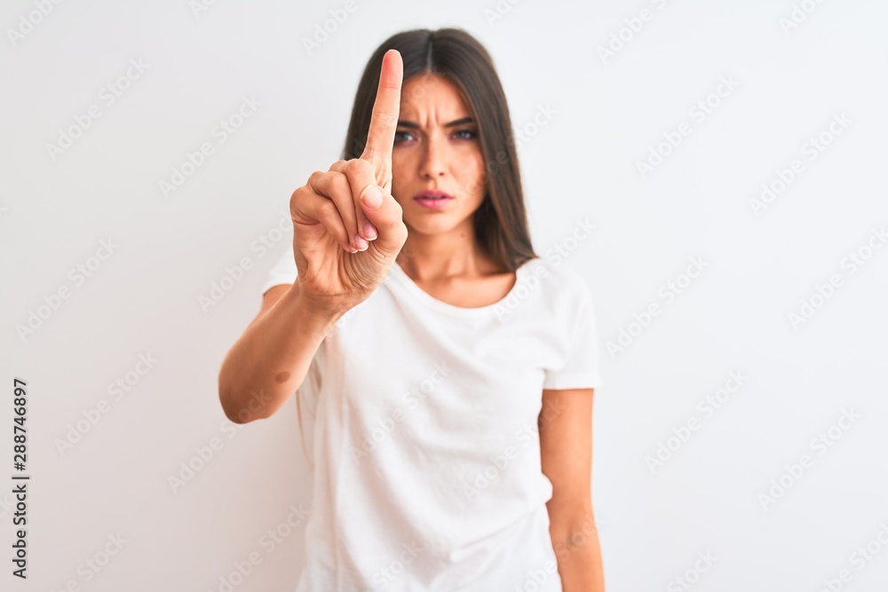Young beautiful woman wearing casual t-shirt standing over isolated white background Pointing with finger up and angry expression, showing no gesture Young beautiful woman wearing casual t-shirt standing over isolated white background Pointing with finger up and angry expression, showing no gesture