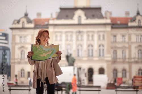 One mature woman, in old European city, holding a city map in her hands, while searching in it. © HD92