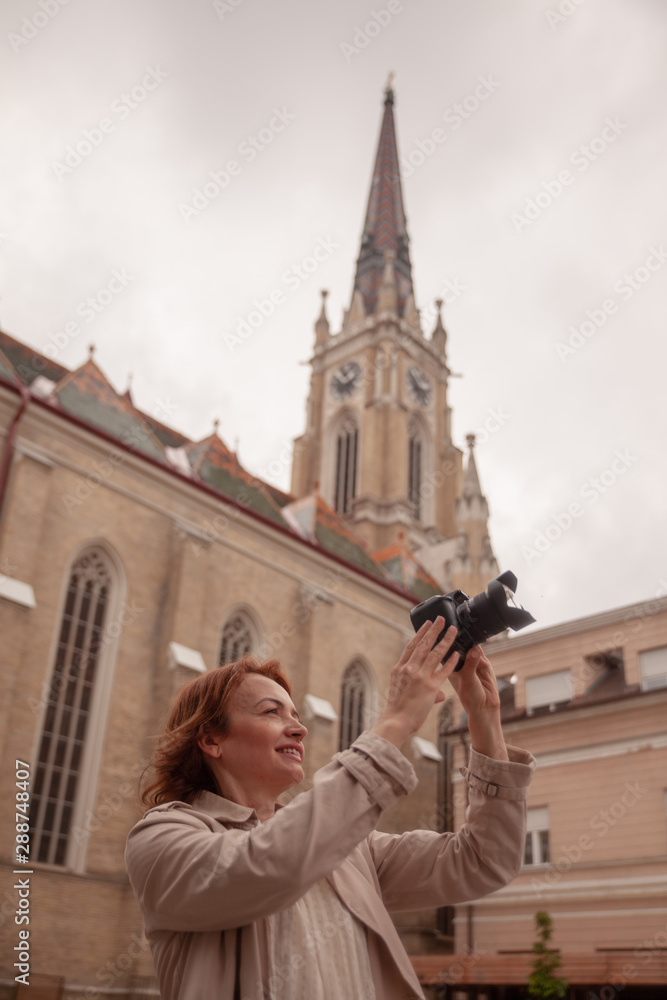 One woman, photographing cathedral in a city. rear view, back.