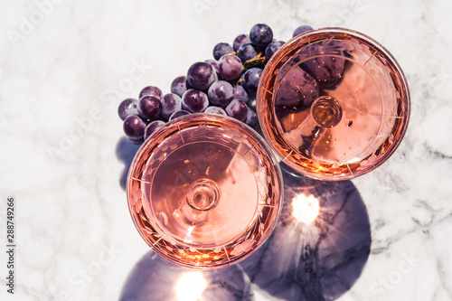 Two crystal stemmed glasses with rose wine on marble table outdoors in a cafe. Aperitif and relax time