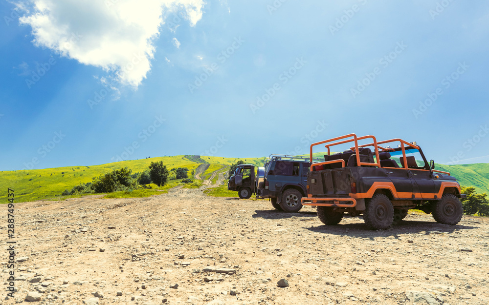 Cars in the nature. Off-road on the background of a meadow and blue sky. Outdoor activities and travel