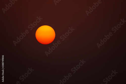yellow and red perfectly round glowing sun against a dark background © itsajoop