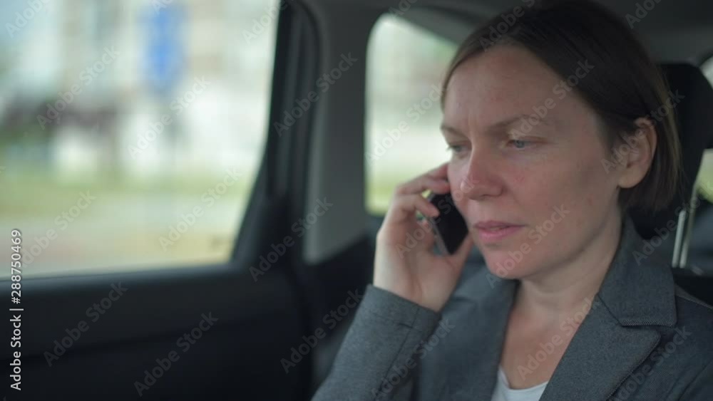 Businesswoman talking on mobile phone on car back seat Businesswoman talking on mobile phone on car back seat
