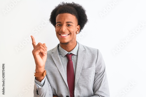 Young african american businessman wearing suit standing over isolated white background with a big smile on face, pointing with hand and finger to the side looking at the camera.