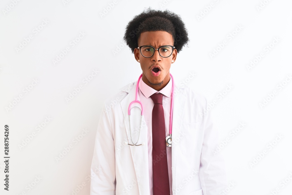 Young african american doctor man wearing pink stethoscope over isolated white background afraid and shocked with surprise expression, fear and excited face. Young african american doctor man wearing pink stethoscope over isolated white background afraid and shocked with surprise expression, fear and excited face.