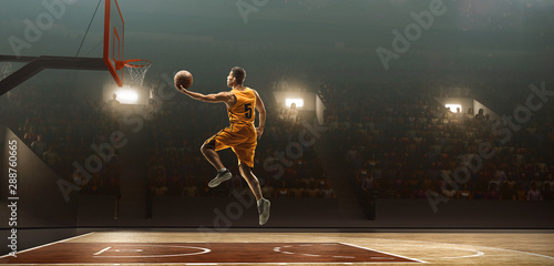 Basketball player on sports arena in action with the ball. Slam dunk