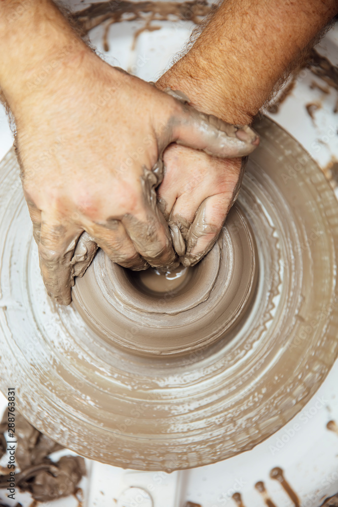 View at an artist makes clay pottery on a spin wheel View at an artist makes clay pottery on a spin wheel