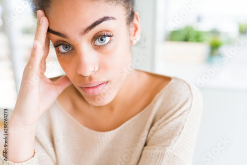 Beautiful young african american woman with blue eyes relaxing at home, with confident expression on face