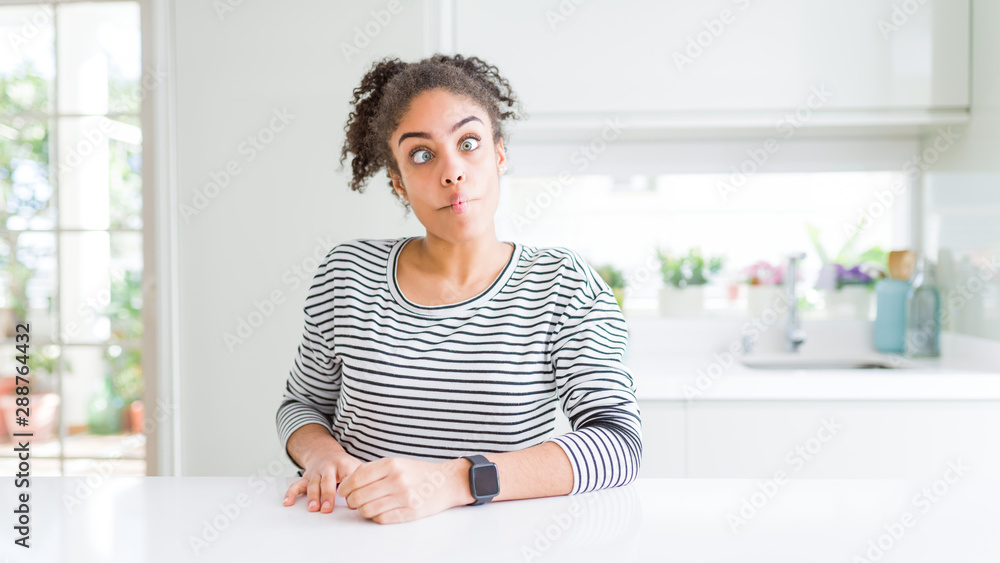Beautiful african american woman with afro hair wearing casual striped sweater making fish face with lips, crazy and comical gesture. Funny expression. Beautiful african american woman with afro hair wearing casual striped sweater making fish face with lips, crazy and comical gesture. Funny expression.