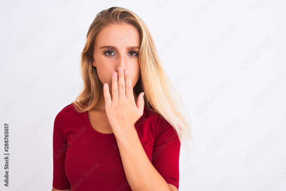 Young beautiful woman wearing red t-shirt standing over isolated white background cover mouth with hand shocked with shame for mistake, expression of fear, scared in silence, secret concept Young beautiful woman wearing red t-shirt standing over isolated white background cover mouth with hand shocked with shame for mistake, expression of fear, scared in silence, secret concept