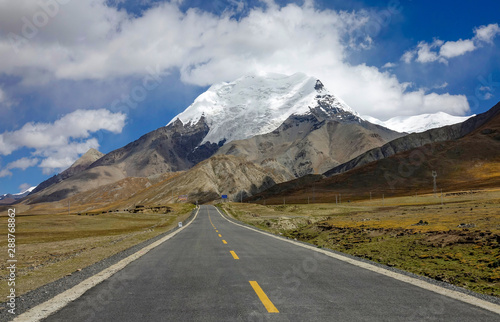 Straight road leads towards the foothills of a majestic Himalayan glacier. © helivideo