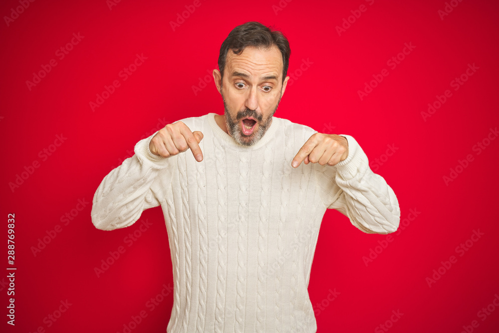 Handsome middle age senior man with grey hair over isolated red background Pointing down with fingers showing advertisement, surprised face and open mouth Handsome middle age senior man with grey hair over isolated red background Pointing down with fingers showing advertisement, surprised face and open mouth