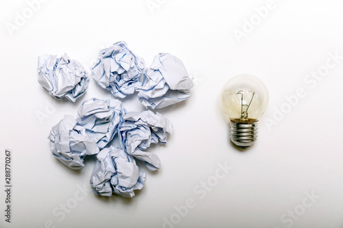 Fototapeta Naklejka Na Ścianę i Meble -  Inspiration concept crumpled paper and light bulb metaphor for good idea. White crumpled paper and light bulb on white background, flat lay.