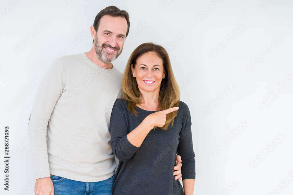 Beautiful middle age couple in love over isolated background cheerful with a smile of face pointing with hand and finger up to the side with happy and natural expression on face Beautiful middle age couple in love over isolated background cheerful with a smile of face pointing with hand and finger up to the side with happy and natural expression on face