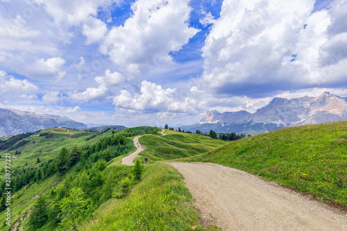 A picturesque rural road with cyclist riding mountain bike in Italian Dolomites, Alto Adige. photo