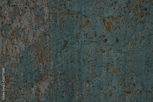 wall of a metal fence with rusty spots under a wash-out layer of blue paint