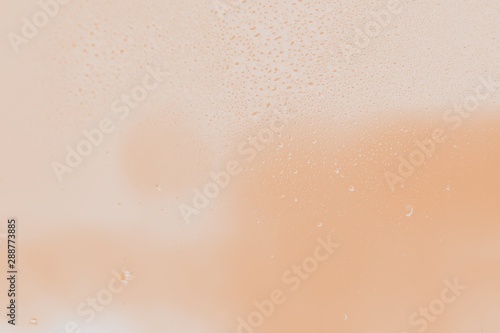 Raindrops on window glass. Peach color gradient background