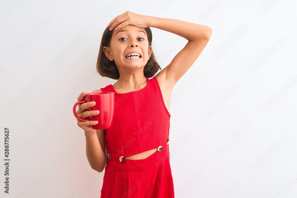 Beautiful child girl holding red cup of tea standing over isolated white background stressed with hand on head, shocked with shame and surprise face, angry and frustrated. Fear and upset for mistake. Beautiful child girl holding red cup of tea standing over isolated white background stressed with hand on head, shocked with shame and surprise face, angry and frustrated. Fear and upset for mistake.