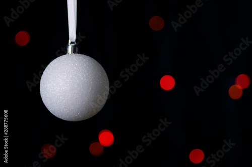 White Christmas ball on a black background with red lights.With copy-space.