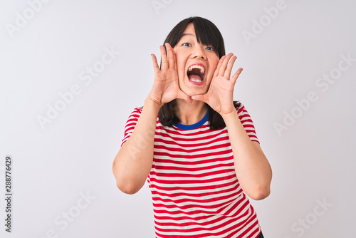 Young beautiful chinese woman wearing red striped t-shirt over isolated white background Smiling cheerful playing peek a boo with hands showing face. Surprised and exited