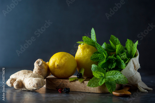 Ginger, lemons and mint leaves on dark background. Ginger tea, drink ingredients, cold and autumn time. photo