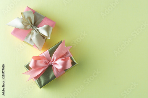 Goldenand pink gift isolated on yellow background. Birthday  Christmas party mock up. Copy space.