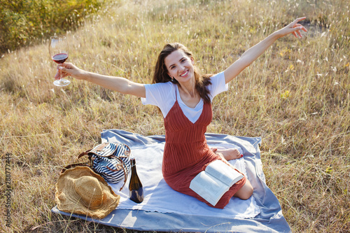 Happy young woman with a glass of wine at sunset.