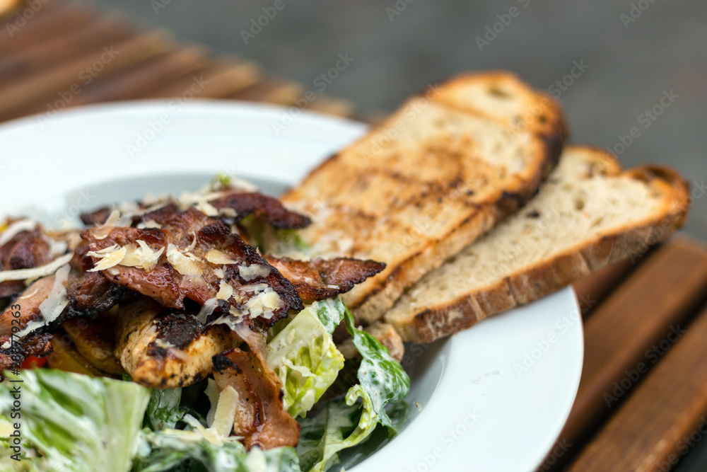 Close up shot of caesar salad in cafe, organic green vegetable with parmesan cheese and bacon Close up shot of caesar salad in cafe, organic green vegetable with parmesan cheese and bacon