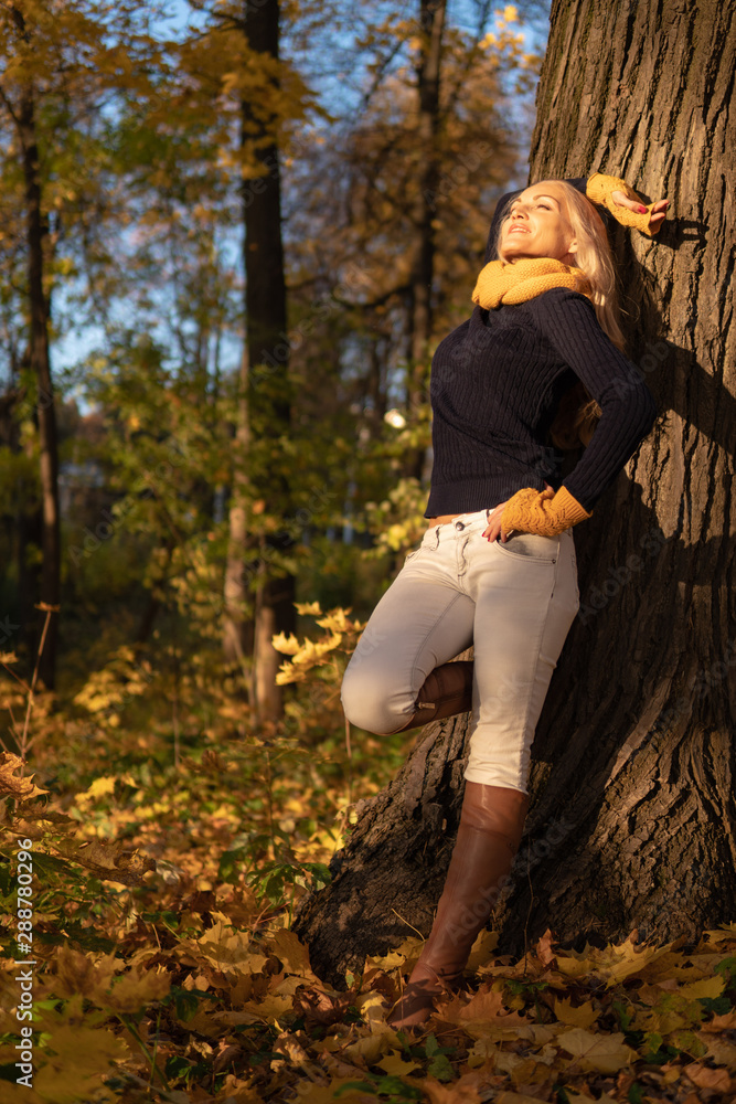The girl rests on a tree and is photographed at sunset in cowboy clothes, brown boots
