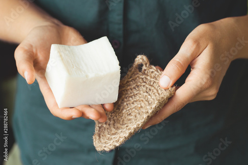 Eco-friendly cleaning kit. Organic soap and jute washcloth in the woman's hand. Zero waste concept, plastic-free, eco-friendly shopping, vegan