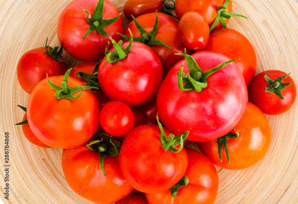 Wooden dish with different ripe tomatoes on white background. Wooden dish with different ripe tomatoes on white background.
