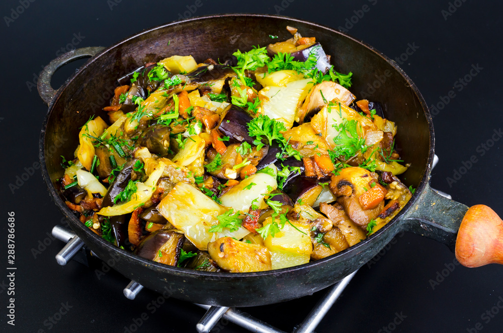 Fried eggplant, paprika and different vegetables in pan on black background Fried eggplant, paprika and different vegetables in pan on black background