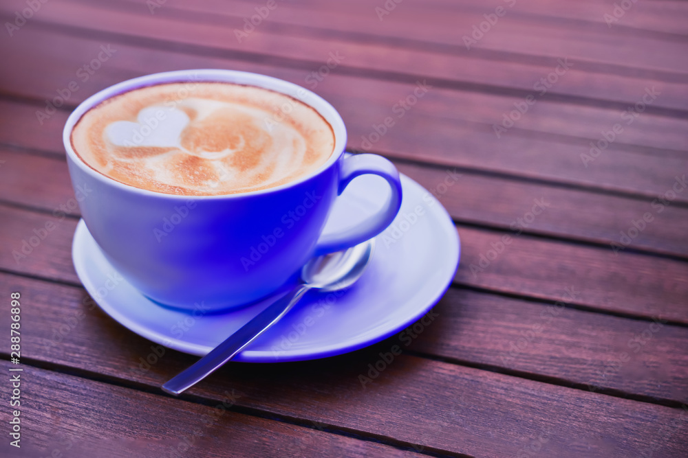  Cup of coffee in neon light on wooden table. Copy space