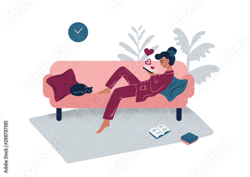 Young woman using a gadget while lying on a sofa at home.
