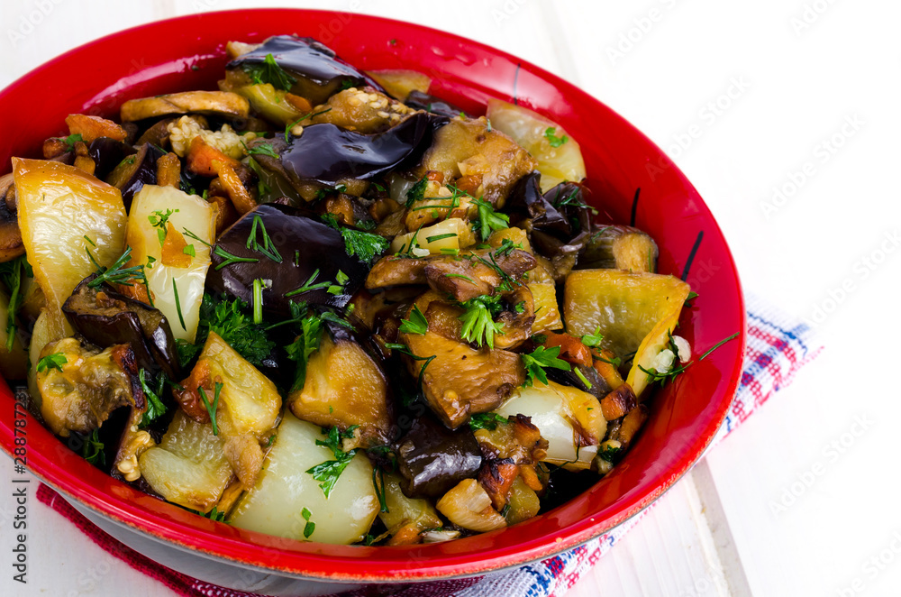 Vegetable saute with eggplants in ceramic bowl on white wooden table