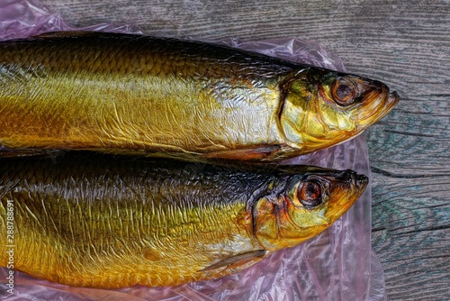 two brown herring fish lie on cellophane and gray table