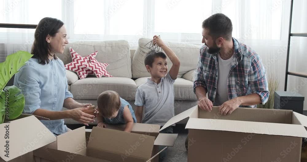 Family unpacking boxes and arranging objects in new apartment Family unpacking boxes and arranging objects in new apartment