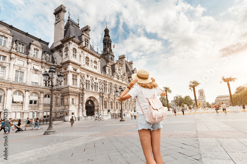 Photography Attractive girl traveler with a cute backpack enjoys the view of the stunning Gothic architecture of the old town Hall in Paris